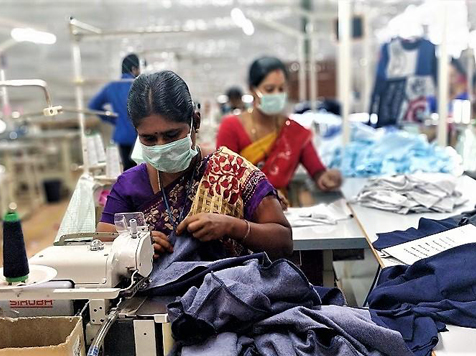Operators stitching garments on industrial sewing machines